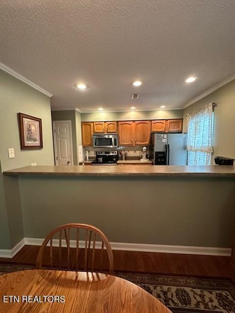 5230 Brig Ln, Knoxville, TN 37914 - kitchen with appliances with stainless steel finishes, brown cabinets, wood finished floors, ornamental molding, and a peninsula