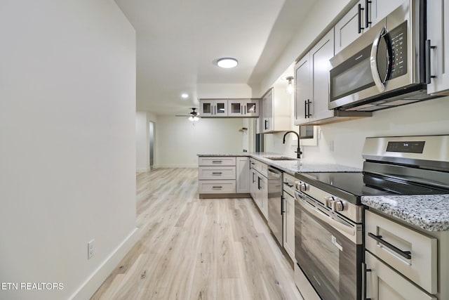 1122 N Shady Lane Loop, Clarkrange, TN 38553 - kitchen with stainless steel appliances, a sink, light wood-style flooring, light stone countertops, and baseboards