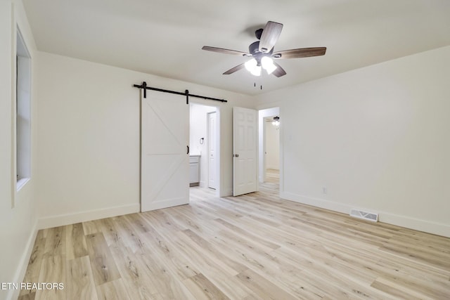 1122 N Shady Lane Loop, Clarkrange, TN 38553 - unfurnished bedroom featuring baseboards, light wood finished floors, a barn door, connected bathroom, and a ceiling fan