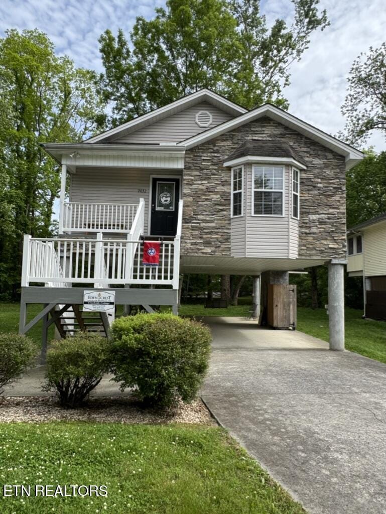 2032 Slippery Rock Cir, Pigeon Forge, TN 37862 - view of front of property with a carport, driveway, a porch, stone siding, and a front yard