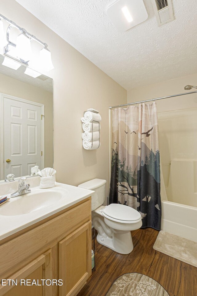 2032 Slippery Rock Cir, Pigeon Forge, TN 37862 - bathroom featuring wood finished floors, toilet, vanity, a textured ceiling, and shower / bath combo