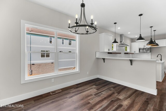 270 W Main St, Dandridge, TN 37725 - kitchen with wall chimney range hood, stainless steel microwave, a kitchen bar, a chandelier, and light countertops