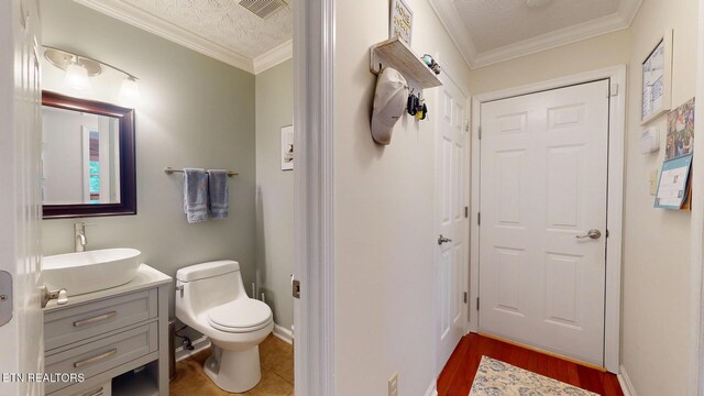 1859 Poplar Hill Rd, Knoxville, TN 37922 - half bathroom with vanity, toilet, ornamental molding, a textured ceiling, and wood finished floors