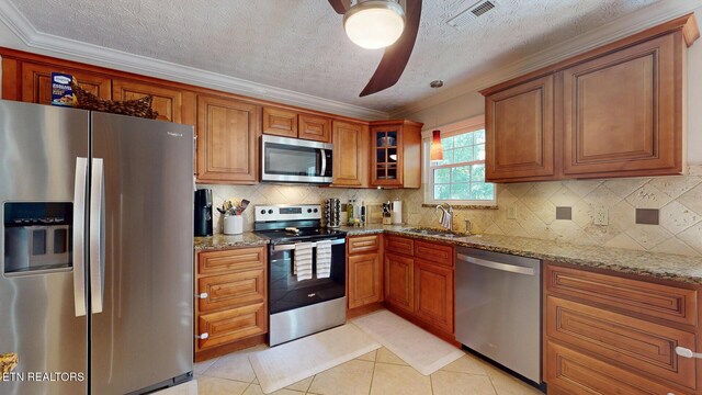 1859 Poplar Hill Rd, Knoxville, TN 37922 - kitchen with stainless steel appliances, a sink, light stone countertops, brown cabinetry, and crown molding