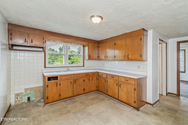 812 W Emerald Ave, Knoxville, TN 37921 - kitchen featuring light countertops, brown cabinetry, a textured ceiling, a sink, and backsplash