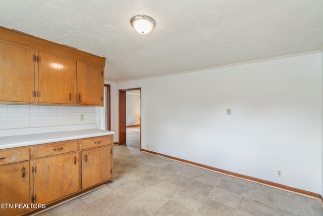 812 W Emerald Ave, Knoxville, TN 37921 - kitchen with light countertops, baseboards, brown cabinetry, a textured ceiling, and crown molding