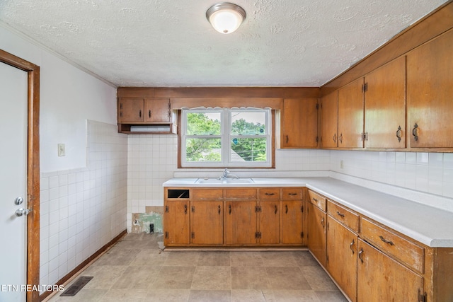 812 W Emerald Ave, Knoxville, TN 37921 - kitchen with a sink, brown cabinets, light countertops, a textured ceiling, and tile walls