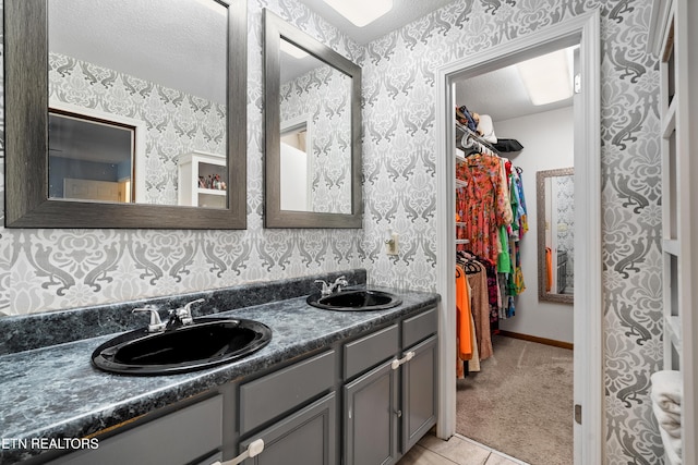 8707 Olde Colony Trl Unit 17, Knoxville, TN 37923 - bathroom with wallpapered walls, double vanity, a spacious closet, tile patterned flooring, and a textured ceiling