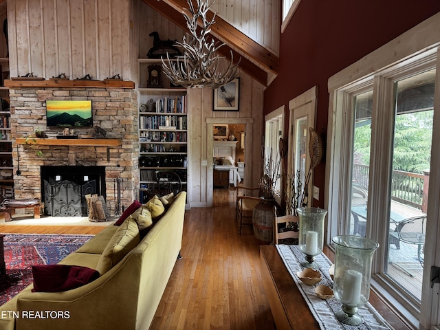 1309 Licklog Hollow Rd, Sevierville, TN 37876 - living area with a stone fireplace, wood-type flooring, a chandelier, wood walls, and high vaulted ceiling
