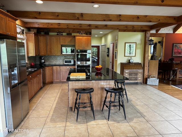 1309 Licklog Hollow Rd, Sevierville, TN 37876 - kitchen featuring appliances with stainless steel finishes, light tile patterned floors, beamed ceiling, tasteful backsplash, and dark countertops