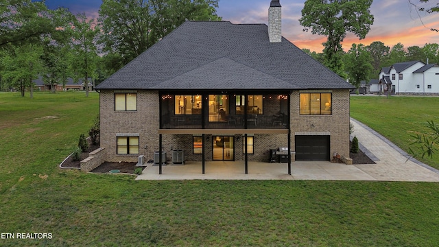 708 Lakeside Ct, Dandridge, TN 37725 - back of house at dusk featuring brick siding, a chimney, a lawn, and a patio area
