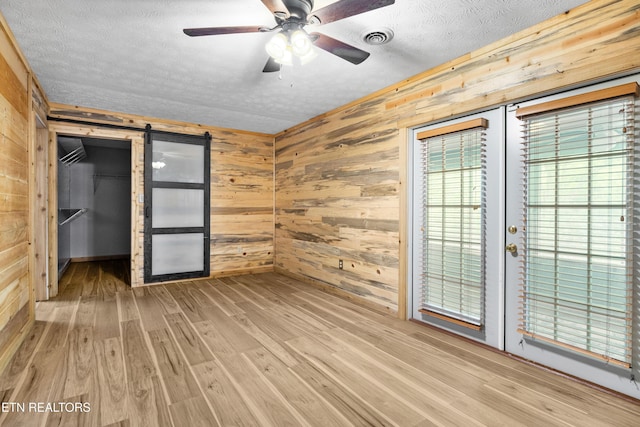 3305 Leonard Huskey Ln, Pigeon Forge, TN 37863 - unfurnished bedroom featuring wood walls, a textured ceiling, wood finished floors, a barn door, and a spacious closet