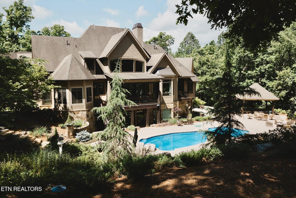 612 Mcfee Rd, Knoxville, TN 37934 - rear view of house featuring stone siding, a sunroom, a patio, an outdoor pool, and a chimney