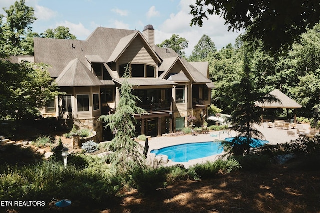 612 Mcfee Rd, Knoxville, TN 37934 - rear view of house featuring stone siding, a sunroom, a patio, an outdoor pool, and a chimney