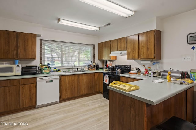 205 Newcastle Rd, Knoxville, TN 37909 - kitchen featuring white appliances, under cabinet range hood, a peninsula, a sink, and light wood-style flooring