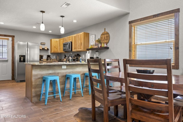 2046 Slippery Rock Cir, Sevierville, TN 37862 - kitchen featuring appliances with stainless steel finishes, light wood-style flooring, open shelves, a peninsula, and light stone counters
