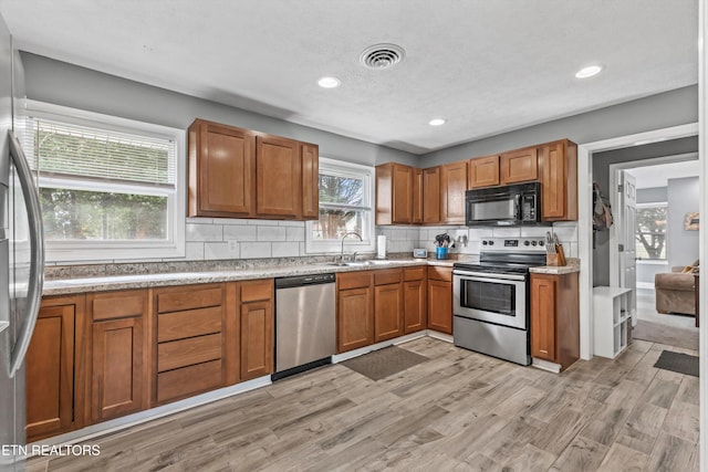 2116 Pleasant View Rd, Knoxville, TN 37914 - kitchen featuring appliances with stainless steel finishes, brown cabinetry, tasteful backsplash, light wood finished floors, and light countertops