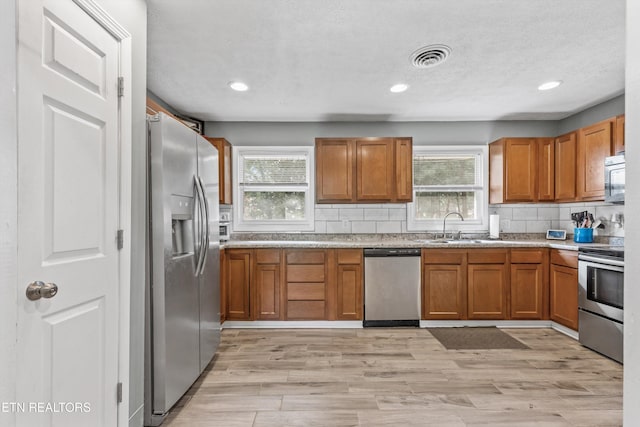 2116 Pleasant View Rd, Knoxville, TN 37914 - kitchen with appliances with stainless steel finishes, brown cabinetry, a sink, backsplash, and healthy amount of natural light