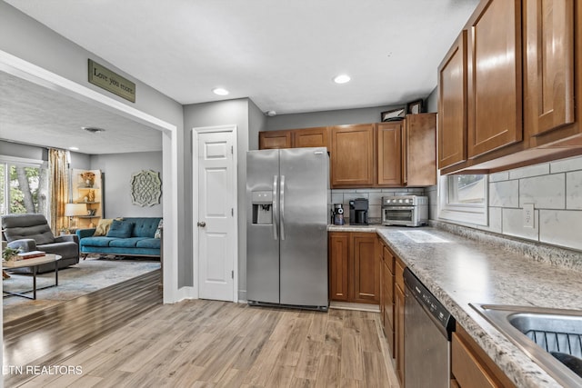 2116 Pleasant View Rd, Knoxville, TN 37914 - kitchen featuring appliances with stainless steel finishes, brown cabinets, light wood-style flooring, light countertops, and open floor plan