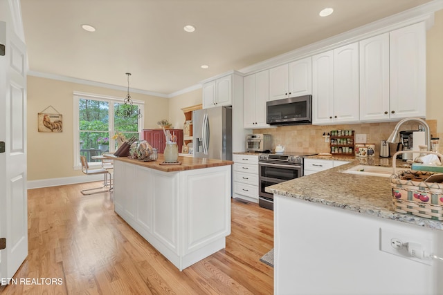 670 Hawk View Dr, Townsend, TN 37882 - kitchen featuring stainless steel appliances, a sink, white cabinets, ornamental molding, and light wood-style flooring