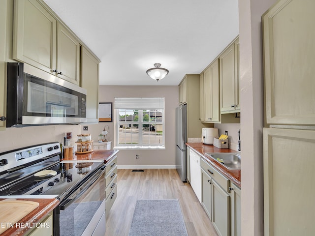 633 Vose Rd Unit G, Alcoa, TN 37701 - kitchen with stainless steel appliances, cream cabinets, light wood-style flooring, a sink, and baseboards