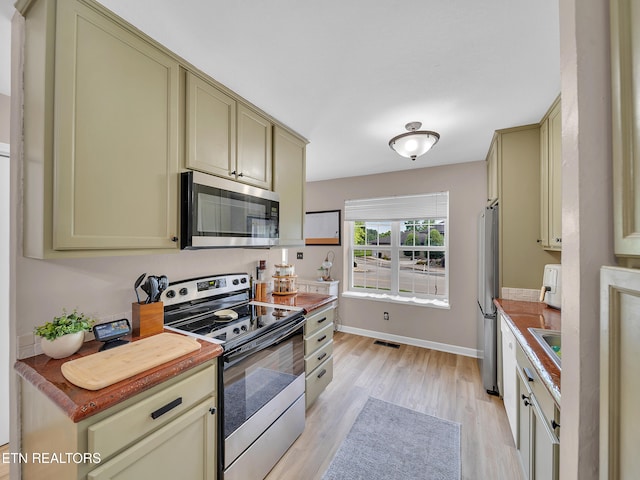 633 Vose Rd Unit G, Alcoa, TN 37701 - kitchen with stainless steel appliances, cream cabinetry, light wood-style floors, baseboards, and a sink