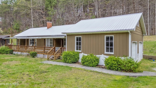 2009 Tellico Reliance Rd, Reliance, TN 37369 - view of front of home featuring a chimney, a porch, metal roof, a front lawn, and a wooded view