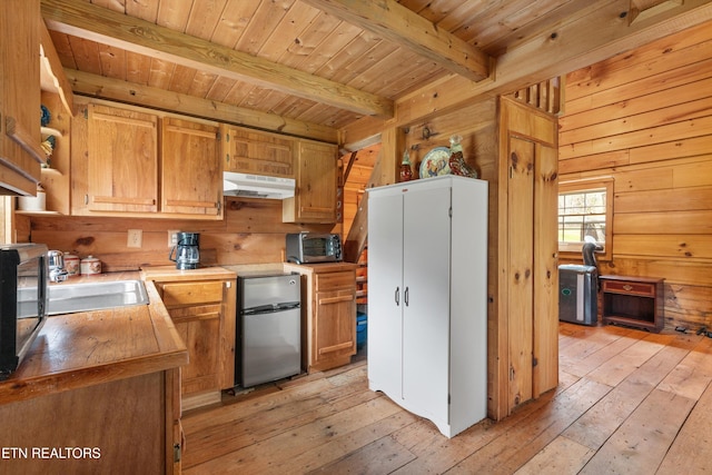 2009 Tellico Reliance Rd, Reliance, TN 37369 - kitchen with under cabinet range hood, freestanding refrigerator, light wood-type flooring, wooden ceiling with exposed beams, and wooden walls
