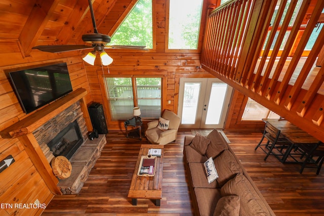 556 Wildwood Forest Way, Sevierville, TN 37876 - living room featuring wood-type flooring, a stone fireplace, wooden walls, a ceiling fan, and french doors