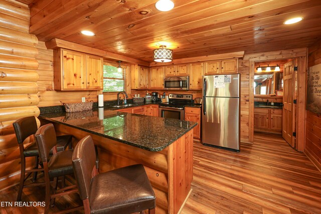 556 Wildwood Forest Way, Sevierville, TN 37876 - kitchen with stainless steel appliances, a sink, a peninsula, light wood-type flooring, and log walls