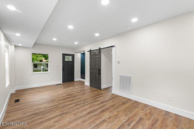 501 Dodson Ave, Englewood, TN 37329 - empty room with a barn door, baseboards, light wood-style flooring, and recessed lighting