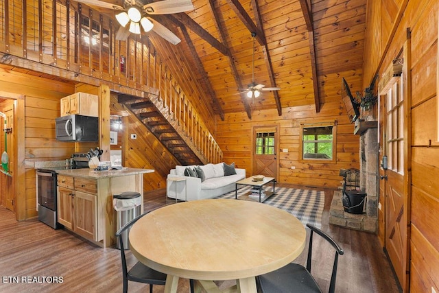 4372 Boogertown Rd Apt 2, Sevierville, TN 37876 - dining room with a ceiling fan, wooden walls, light wood-type flooring, wooden ceiling with exposed beams, and stairs