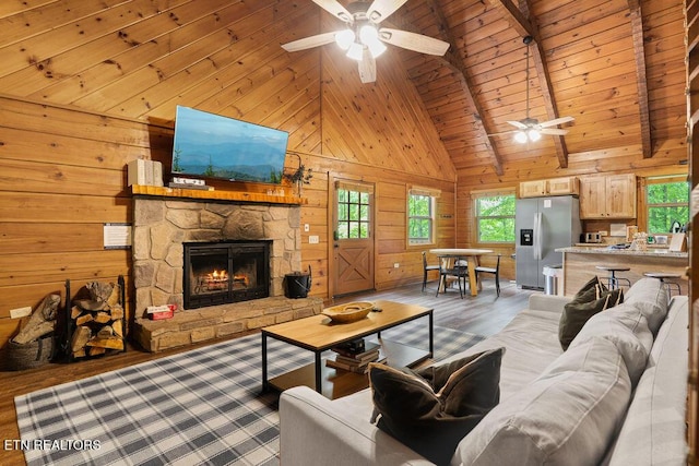 4372 Boogertown Rd Apt 2, Sevierville, TN 37876 - living room featuring a ceiling fan, wood finished floors, wooden walls, high vaulted ceiling, and a stone fireplace