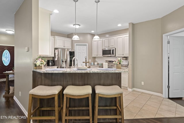 376 Old Holderford Rd, Kingston, TN 37763 - kitchen with stainless steel appliances, a peninsula, a breakfast bar area, light stone counters, and white cabinetry