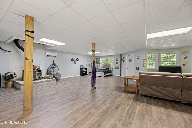 376 Old Holderford Rd, Kingston, TN 37763 - living area featuring wood finished floors, an AC wall unit, a paneled ceiling, a wood stove, and baseboards