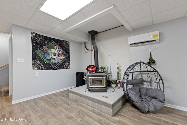 376 Old Holderford Rd, Kingston, TN 37763 - living area with a wall unit AC, a wood stove, a paneled ceiling, wood finished floors, and baseboards