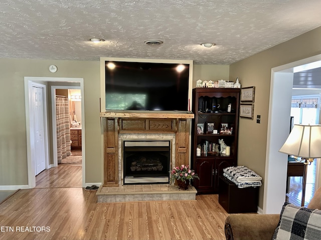 762 Commanche Dr, Jefferson City, TN 37760 - living area featuring light wood-style flooring, a fireplace with raised hearth, baseboards, and a textured ceiling