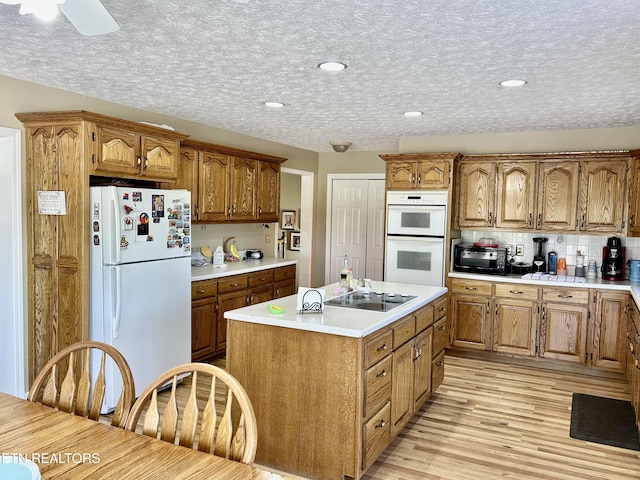762 Commanche Dr, Jefferson City, TN 37760 - kitchen with white appliances, brown cabinets, a center island with sink, light countertops, and light wood-style flooring