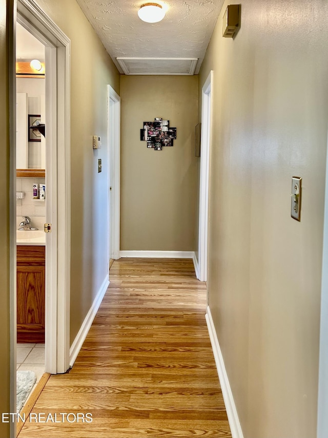 762 Commanche Dr, Jefferson City, TN 37760 - hallway with light wood-style floors, attic access, a textured ceiling, a sink, and baseboards