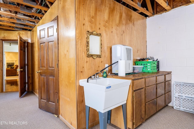 178 Scenic Hill Ln, Lenoir City, TN 37771 - kitchen featuring light colored carpet, dark countertops, wood walls, concrete block wall, and brown cabinets