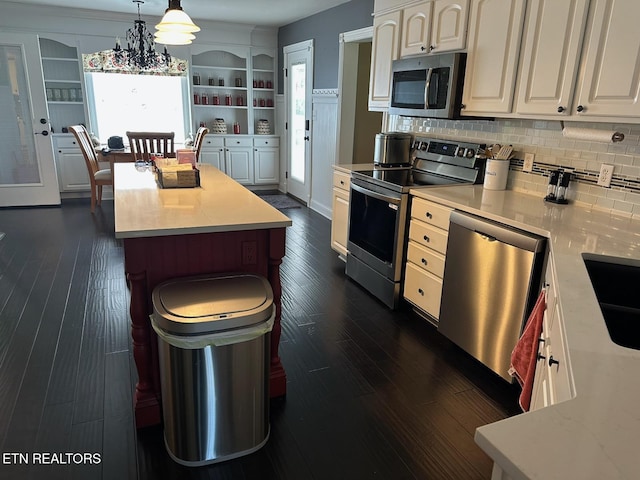 133 Coolidge Rd, Lafollette, TN 37766 - kitchen featuring appliances with stainless steel finishes, light countertops, dark wood finished floors, tasteful backsplash, and hanging light fixtures