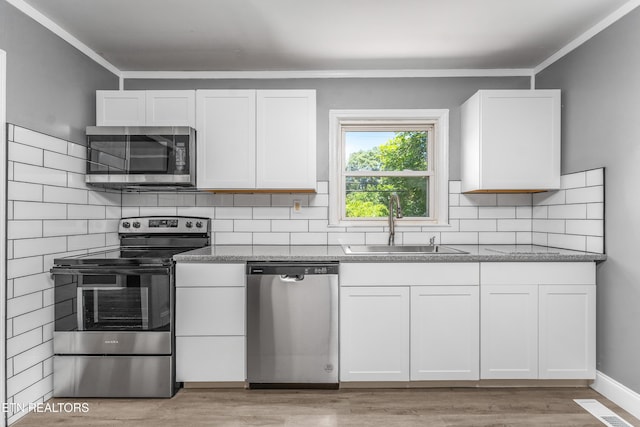 3712 Selma Ave, Knoxville, TN 37914 - kitchen featuring stainless steel appliances, white cabinetry, decorative backsplash, light wood finished floors, and a sink