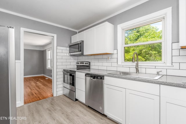3712 Selma Ave, Knoxville, TN 37914 - kitchen with appliances with stainless steel finishes, ornamental molding, a sink, light wood-type flooring, and backsplash