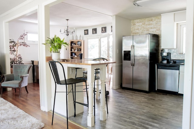109 Cumberland View Dr, Oak Ridge, TN 37830 - kitchen featuring appliances with stainless steel finishes, a chandelier, wood finished floors, tasteful backsplash, and white cabinets