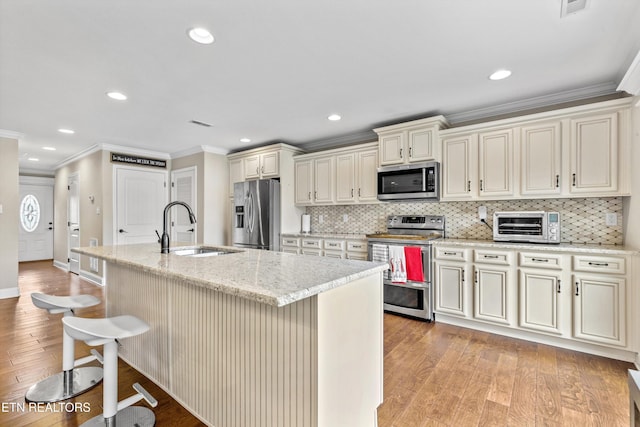 1017 Brighton Dr, Alcoa, TN 37701 - kitchen featuring stainless steel appliances, a sink, crown molding, light wood-style flooring, and a breakfast bar