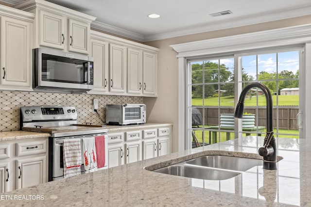1017 Brighton Dr, Alcoa, TN 37701 - kitchen with appliances with stainless steel finishes, a sink, decorative backsplash, light stone countertops, and ornamental molding