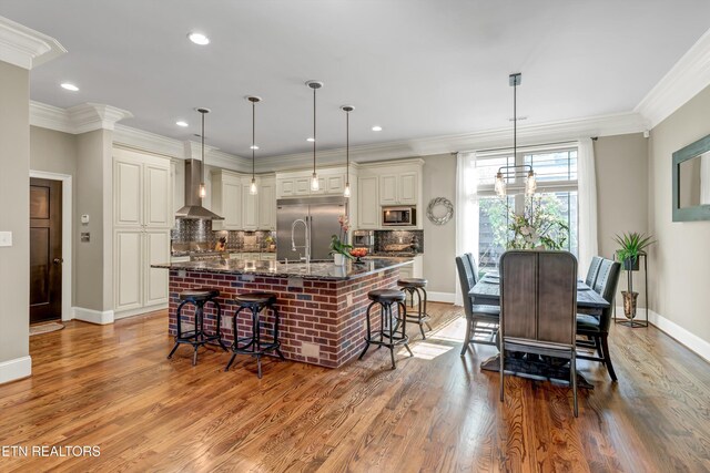 211 Cool Springs Blvd, Knoxville, TN 37934 - kitchen with built in appliances, wall chimney range hood, baseboards, light wood-type flooring, and backsplash