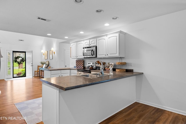1625 Linden Hall Dr, Alcoa, TN 37701 - kitchen with appliances with stainless steel finishes, a peninsula, wood finished floors, white cabinets, and dark countertops