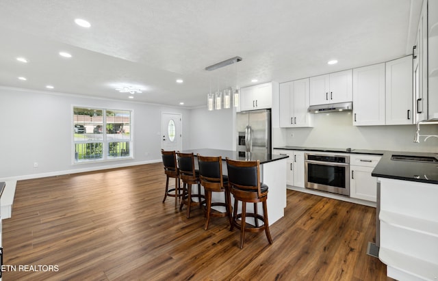 566 Allyson Dr, Kodak, TN 37764 - kitchen featuring stainless steel appliances, under cabinet range hood, dark countertops, dark wood-type flooring, and recessed lighting