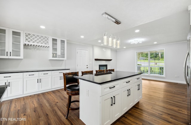 566 Allyson Dr, Kodak, TN 37764 - kitchen with dark countertops, ornamental molding, dark wood finished floors, white cabinetry, and hanging light fixtures